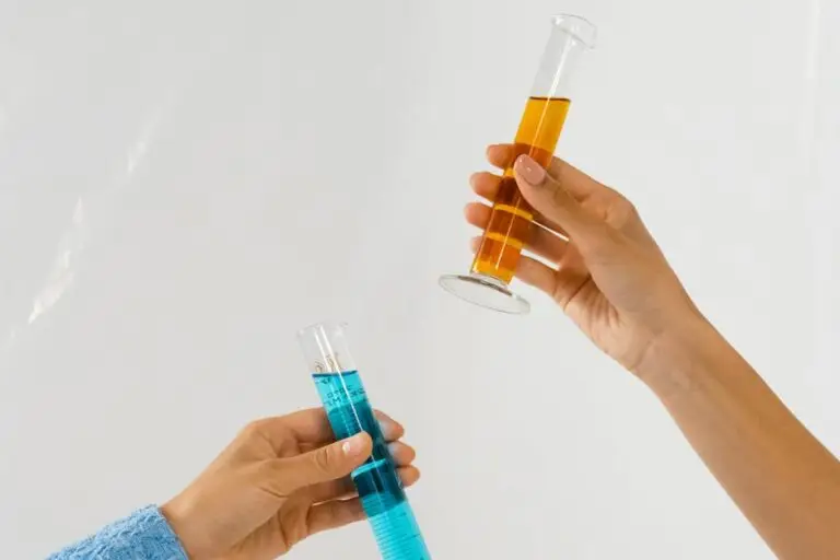 Close-up of hands holding graduated cylinders with blue and orange liquids, symbolizing scientific research.